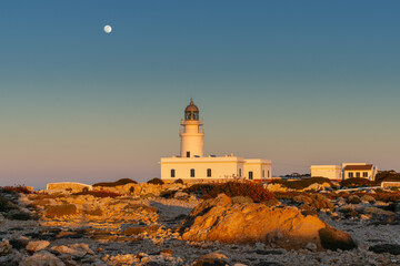 view of the Cap de Cavalleria Lighthouse on Menorca at sunset with a full moon rising