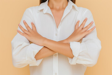 Woman in a white shirt making a stop sign with her hands in a crossed arms pose on a beige background in a closeup portrait