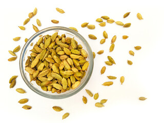 Cardamom pods in glass bowl on white background, Top view with dried cardamom sprinkled everywhere