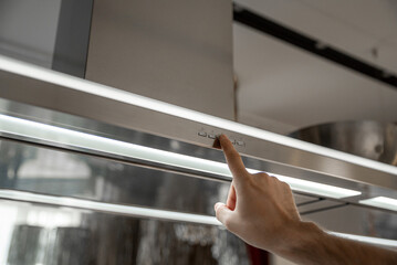 Human hand pushing the button of the kitchen range hood
