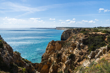 Ponta da Piedade near Lagos in Algarve, Portugal. Cliff rocks and tourist boat on sea. Praia Dona Ana, Estudantes beach. Sunny day. Point of Pity