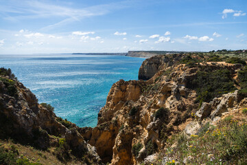 Ponta da Piedade near Lagos in Algarve, Portugal. Cliff rocks and tourist boat on sea. Praia Dona Ana, Estudantes beach. Sunny day. Point of Pity