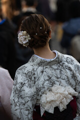 A girl in a bright kimono and flowers in a high hairstyle walks in a crowd of people in Kyoto