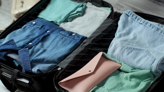 Woman ready for summer holidays, packing suitcase with clothes and accessories