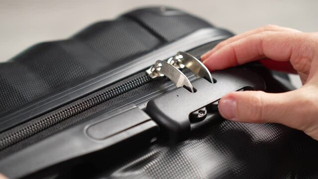 Close up hand close suitcase with combination lock. Hand entering code for open black suitcase