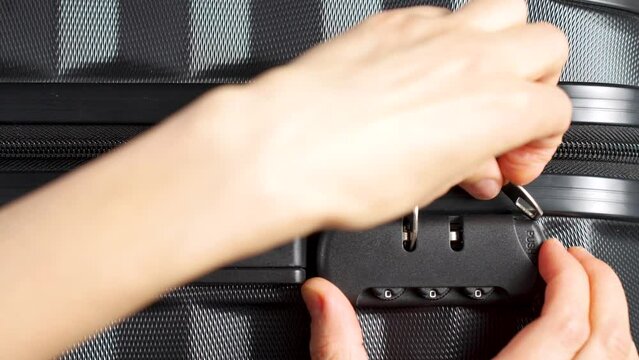 Hand entering code for open black suitcase. Close up hand close suitcase with combination lock.
