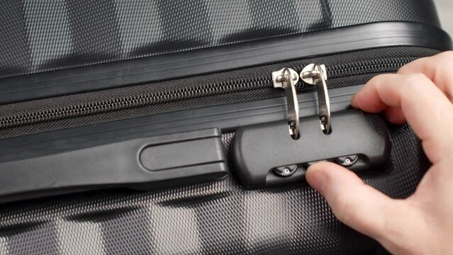 Hand entering code for open black suitcase. Close up hand close suitcase with combination lock.
