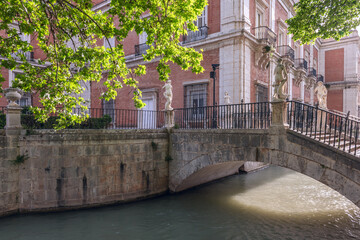 water channel through stone walls with beautiful stone bridges among greenery and leafy trees in...