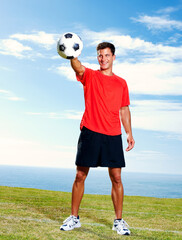 Soccer ball, blue sky and man for practice, grass and fitness for action and football athlete. Summer, body and sports for male person and fit body for wellness and heath, training and game field