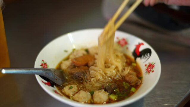  Serve the Thai braised chicken noodles with chopsticks in a white bowl and stainless steel spoon
