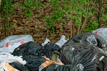 Garbage bag dump in the forest, park. Trash bags. Disposable plastic bags. Waste managment. Environmental issues, pollution. Environmental protection