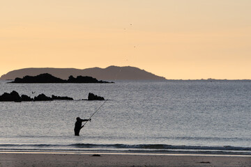 Obraz premium Pêcheur en surfcasting sur une plage de Bretagne en soirée - France