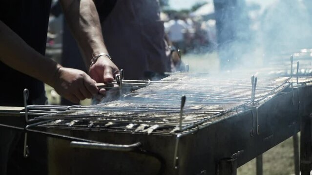 Barbecue de sardines en ext&eacute;rieur en &eacute;t&eacute;, retournement de la grille. Outdoor sardine barbecue in summer.