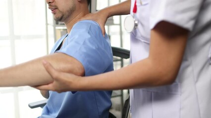 Female doctor is diagnosing pain in a male patient's arm and shoulder in the examination room. Male patient doing arm and shoulder physical therapy. Providing treatment by hospital specialist.
