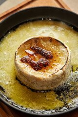 Browned torched Camembert cheese in black iron skillet