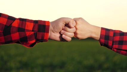 Agronomist farmer hands hitting fist to each other work as team collaboration at corn field...