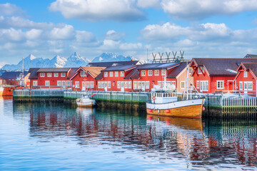 A sailing boat anchored in front of the wooden Rorbu cabins in the Lofoten Islands fishing village,...