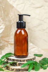 Brown cosmetic bottle with a pump on a wooden podium. Body care, shampoo