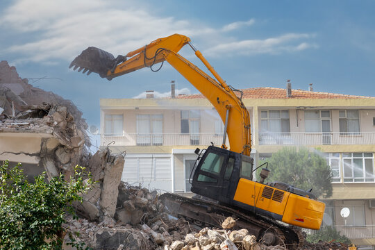 Building demolition excavator with long mechanical arm. Destruction of a house. Heavy machinery, hydraulic construction equipment.