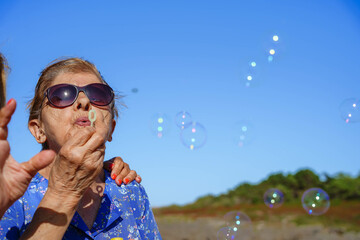 old woman playing with soap bubbles with copy space