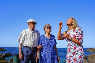 elderly family playing with soap bubbles in the coast