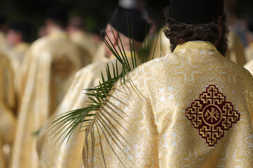Bucharest, Romania - April 27, 2024: Romanian Orthodox priests holding palm leaves walk on the...