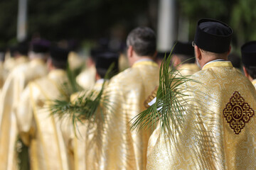 Bucharest, Romania - April 27, 2024: Romanian Orthodox priests holding palm leaves walk on the...