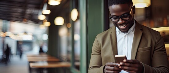 Handsome african man drinking coffee and reading the latest news on his cellphone in cafe copy space