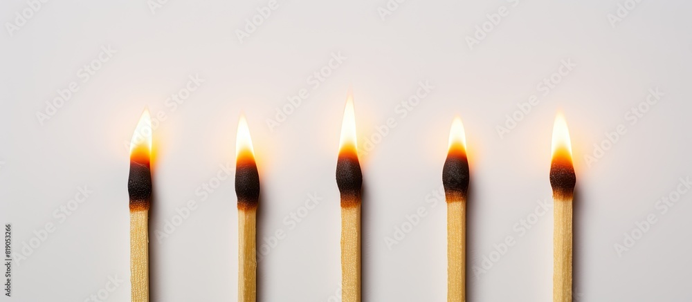 Poster A copy space image of a row of three matches one of which is lit burning on a white background