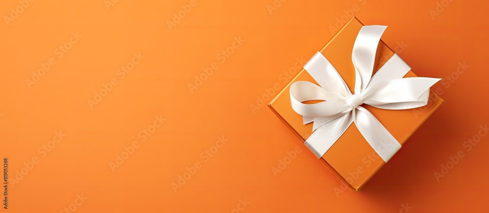Aufkleber top view christmas present box with white bow on orange background with copy space
