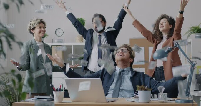 Loop of overjoyed businesspeople catching money falling from above enjoying successful business in office. Finance and teamwork concept.
