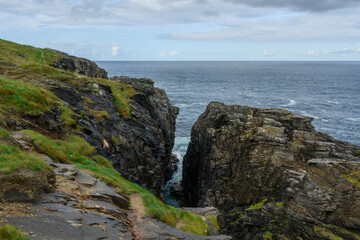 Rocky Cliff Overlooks Ocean on Cloudy Day