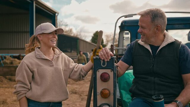 Mature male farm worker sitting on tailgate of off road farm vehicle talking with female colleague - shot in slow motion