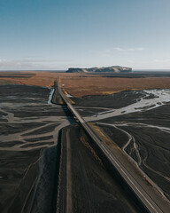 Aerial view of a bridge over a river delta with Hjörleifshöfði mountain in South Iceland