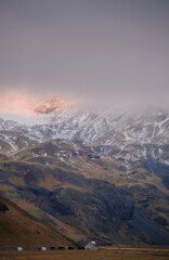 Dramatic view of mist-covered mountains with snow patches in South Iceland