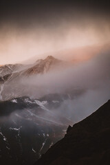 Moody view of misty, snow-capped mountains at sunset in South Iceland