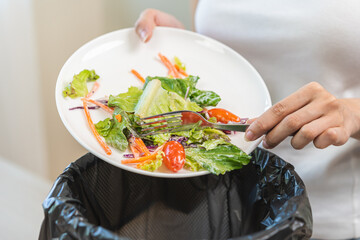 Compost from leftover food asian young housekeeper woman hand holding salad plate use fork scraping...