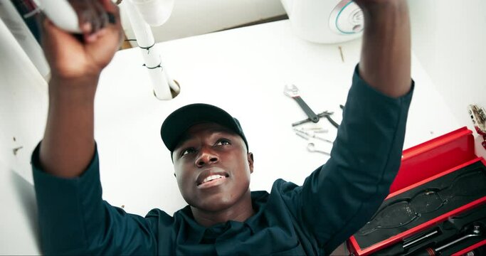 Black man, plumbing and pipe with repair for maintenance, leak or fix on sink or service at home. Young African, male person or plumber working on faucet, basin or water leakage in kitchen at house