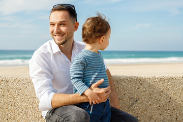 Young happy father with his little son on the embankment against the backdrop of the sea.