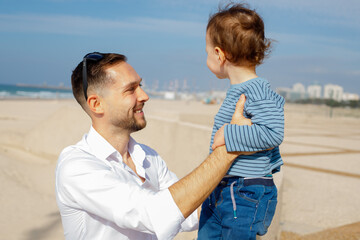 Young happy father with his little son on the embankment against the backdrop of the sea.