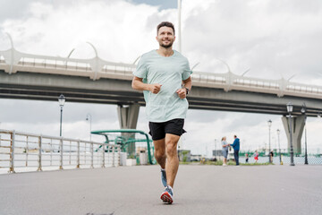 A man runs on a waterfront path, viewed from behind, with a cityscape in the background.