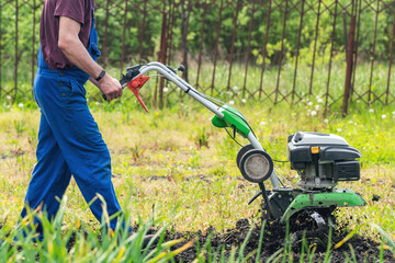 Farmer man plows the land with a cultivator preparing the soil for sowing