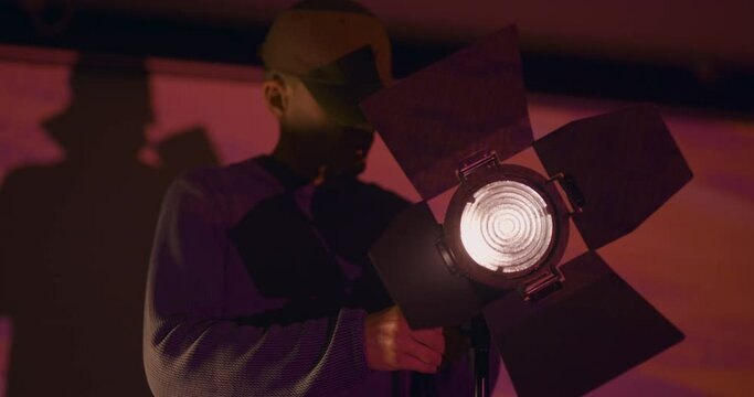 Technician setting up lights on film set