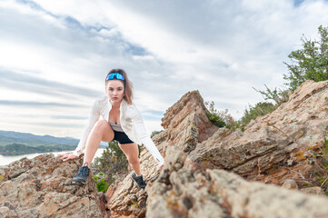 Young woman climbing on rocks above lake