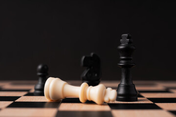 White chess king fallen near black chess king black background
