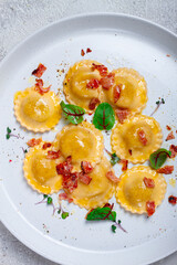 fresh ravioli, with butter, spices and herbs, fried bacon, on the table, top view, light background, no people,