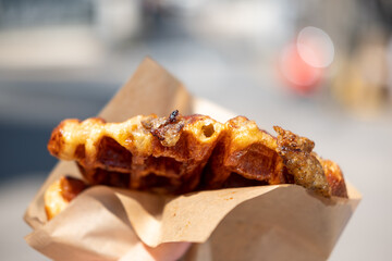 Hand holding Croffle with truffle. It is a hybrid of a croissant and waffle which is a popular pastry in South Korea