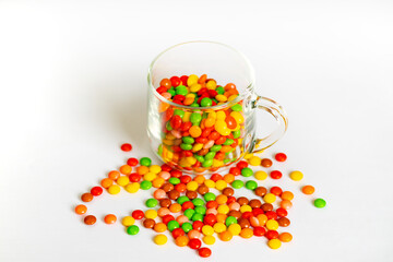 Round candy, jelly beans multi colored in a glass cap on a white background, top view. large variety sweets and candies with copy space.
