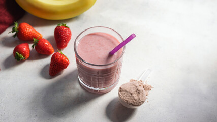 Strawberry and banana smoothie, protein drink in a glass, measuring scoop with whey protein powder, blended cocktail, milkshake