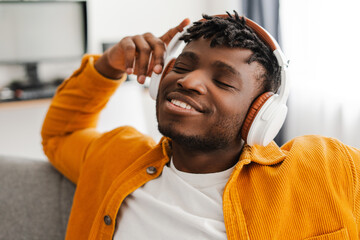 Closeup smiling, handsome, overjoyed African American man listening to music in headphones